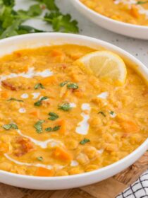 Instant Pot Coconut Red Lentil Soup in a white bowl with a lemon slice and cilantro for garnish