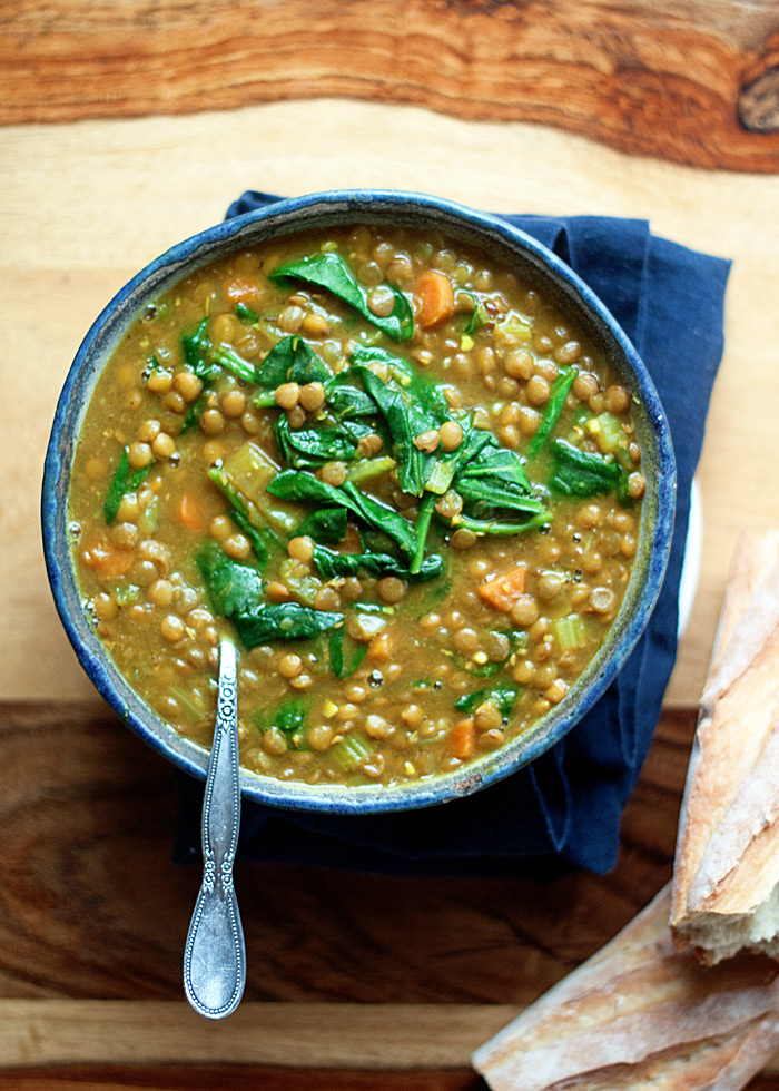 A blue ceramic bowl full of Instant Pot Golden Lentil Soup with a blue napkin in the background on a wooden table. 