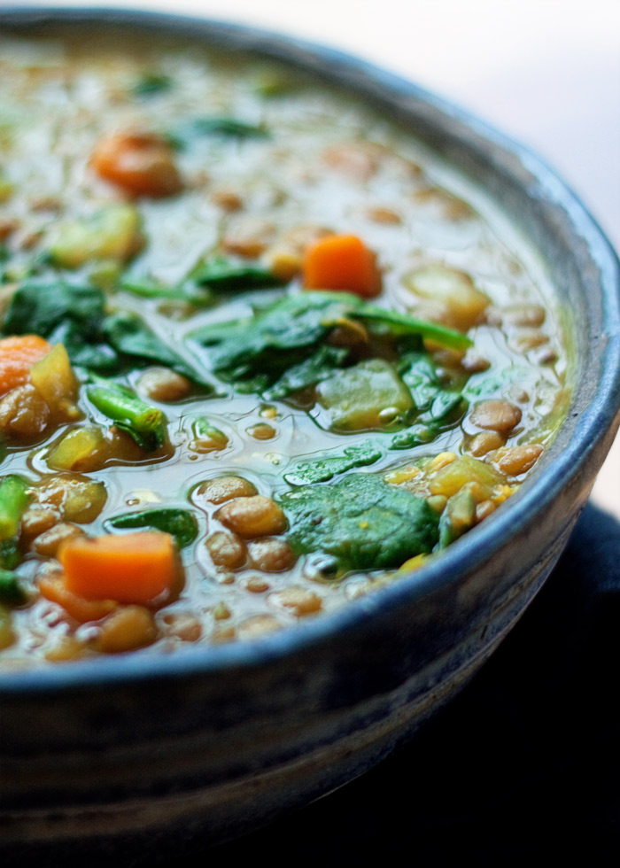 Close-up of a blue bowl of golden lentil and spinach soup