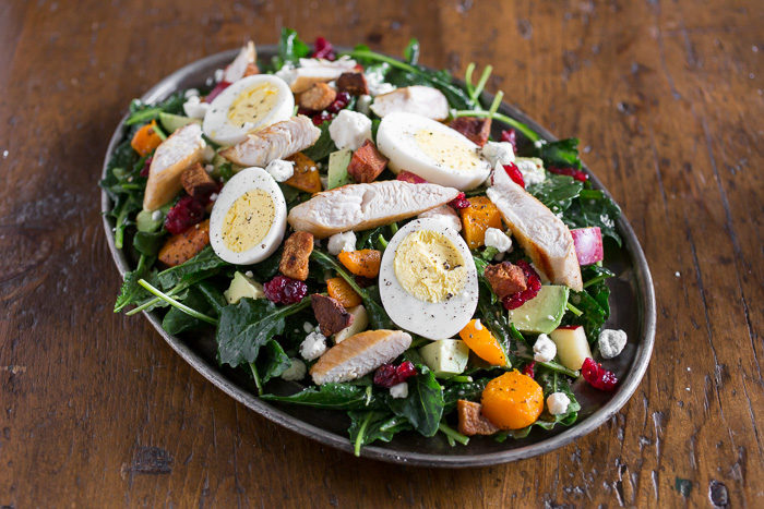 A bowl of winter kale salad topped with chicken. 