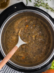 Instant Pot French Lentil Soup with Herbs & Red Potatoes in the Instant Pot, being scooped out by a ladle
