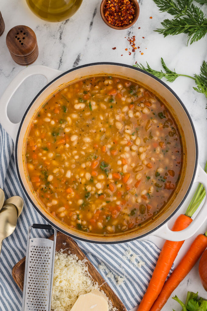 Vegetarian Navy Bean Soup in a pot with veggies and a napkin surrounding