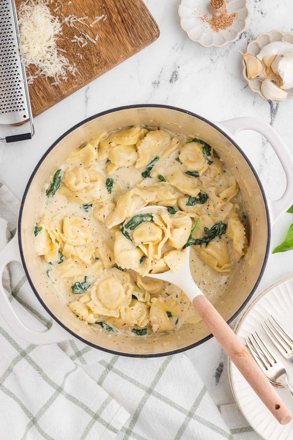 A ladle scoops out a serving of creamy one-pot fettuccine Alfredo with spinach