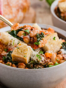 A gold spoon pulls out a spoonful of ribollita