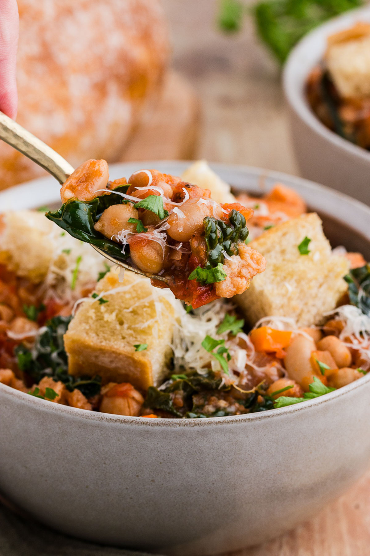A gold spoon pulls out a spoonful of ribollita