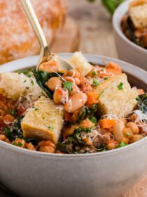 A gold spoon pulls out a spoonful of ribollita