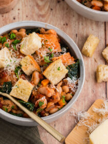 A top view of a bowl of ribollita Toscana in a white bowl with a gold spoon
