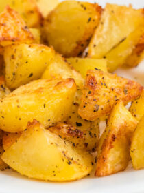 Close-up of crisp roasted Yukon gold potatoes on a white plate.