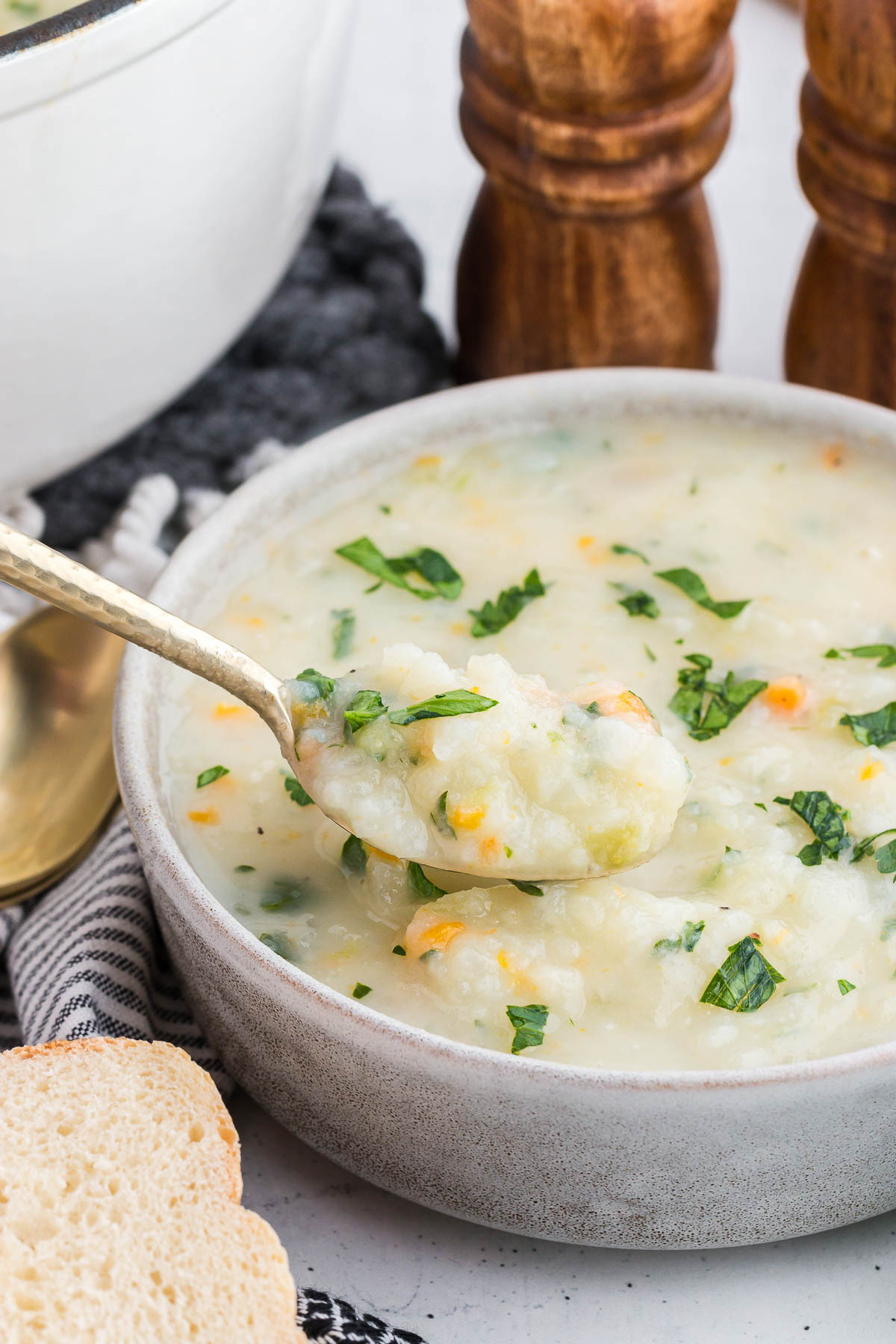 A spoonful of potato soup is scooped out of a white bowl.