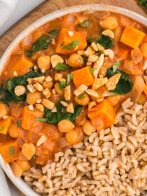 Top view of Slow Cooker Sweet Potato, Chickpea, & Peanut Stew with brown rice in a white bowl.