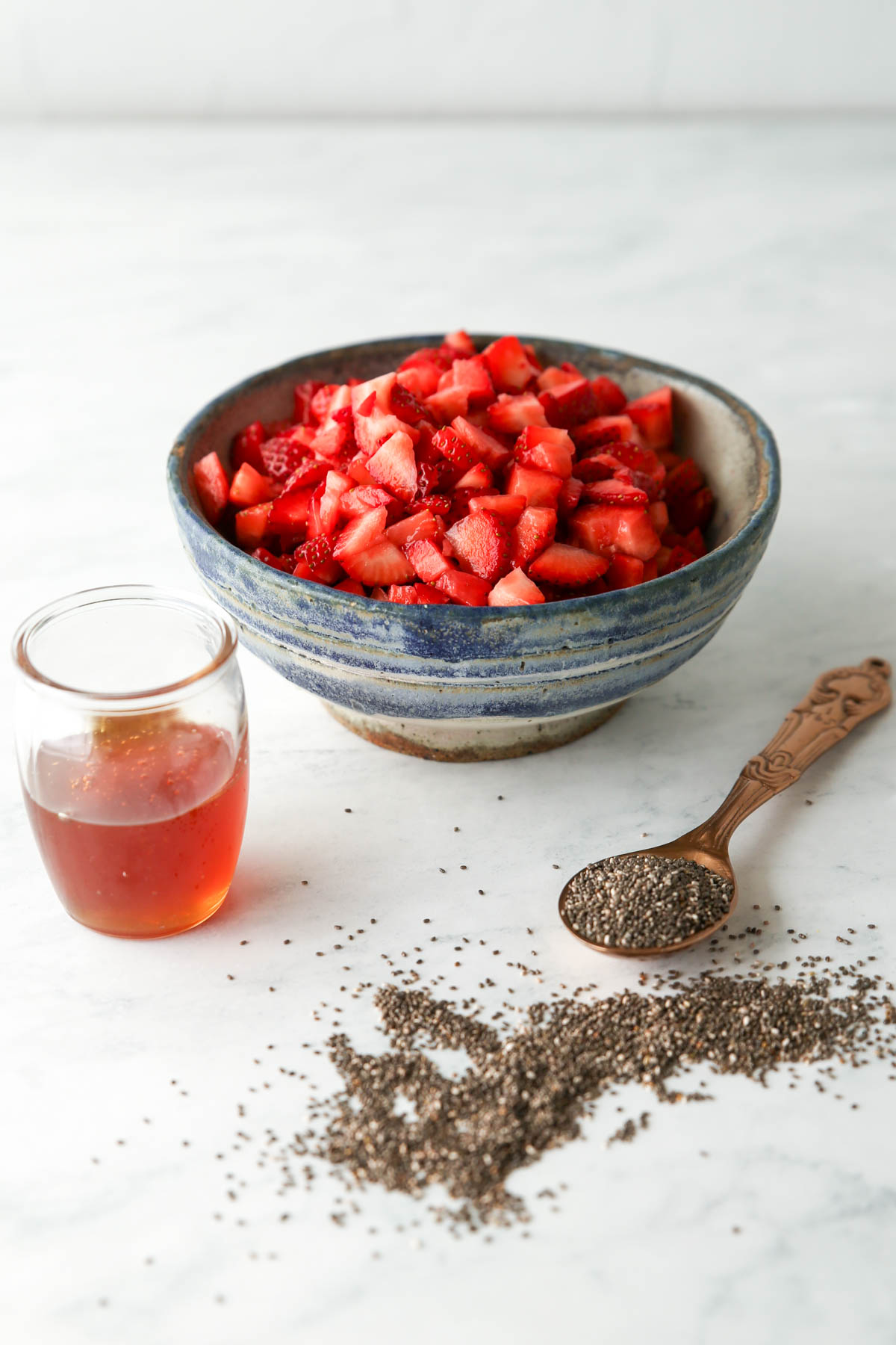 Ingredients for strawberry chia seed jam: diced strawberries, honey, and chia seeds
