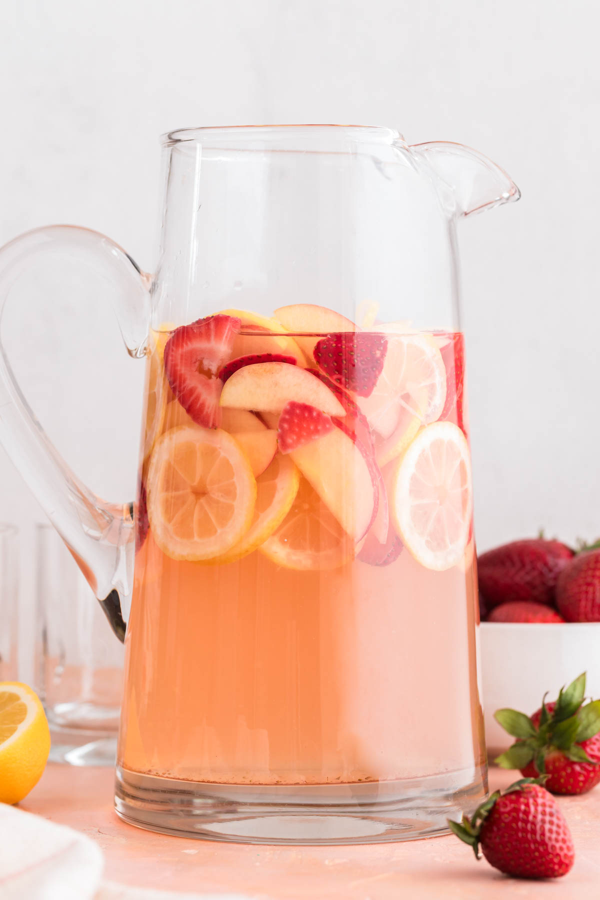 Pink strawberry sangria in a clear glass pitcher.