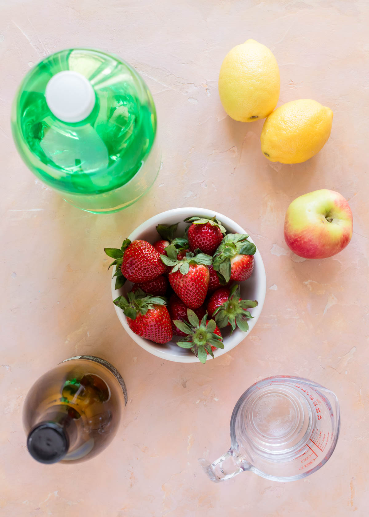 Ingredients for simple strawberry sangria include lemons, apples, strawberries, rum, white wine, and lemon lime soda.