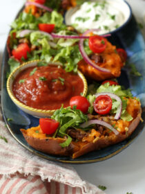 A blue platter with taco sweet potatoes, salsa, and sour cream.