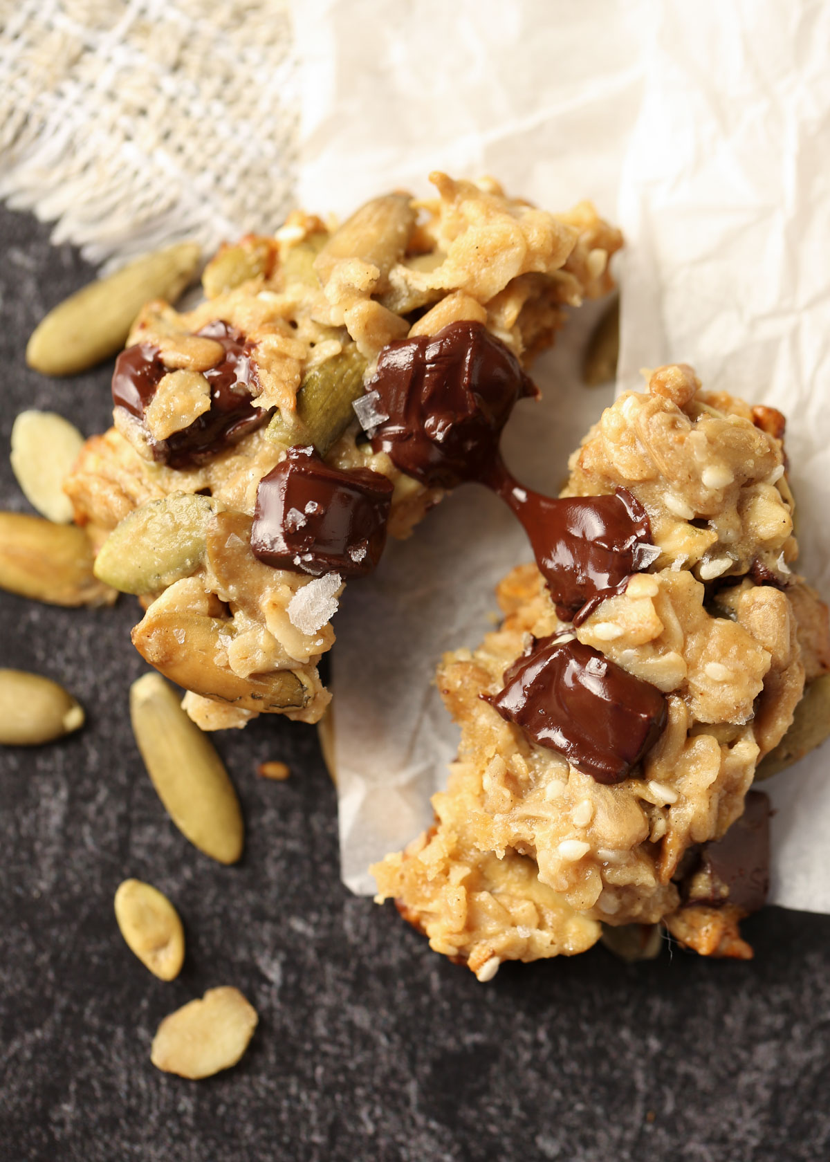 A tahini seed cookie broken in half with melty chocolate.