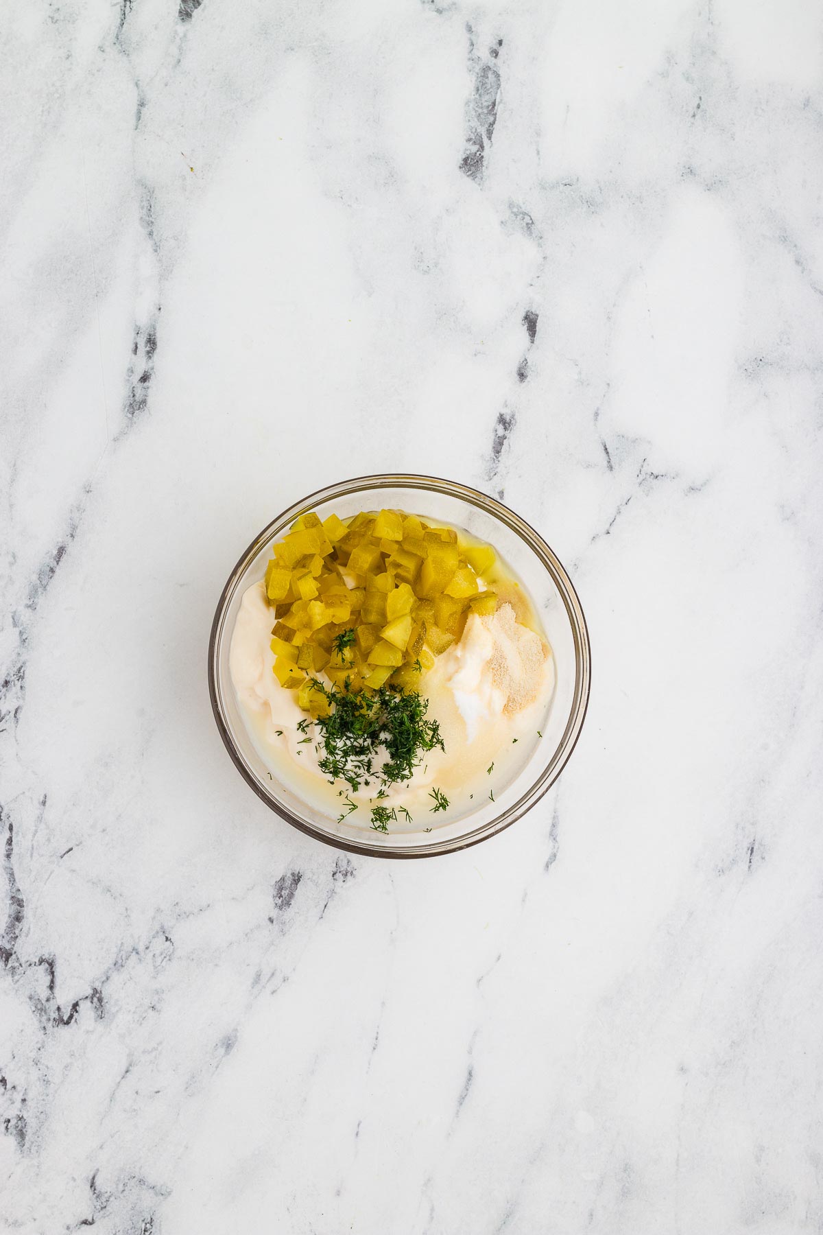 Ingredients for tartar sauce added to a bowl