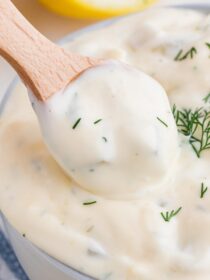 A small wooden condiment spoon scoops tartar sauce out of a bowl