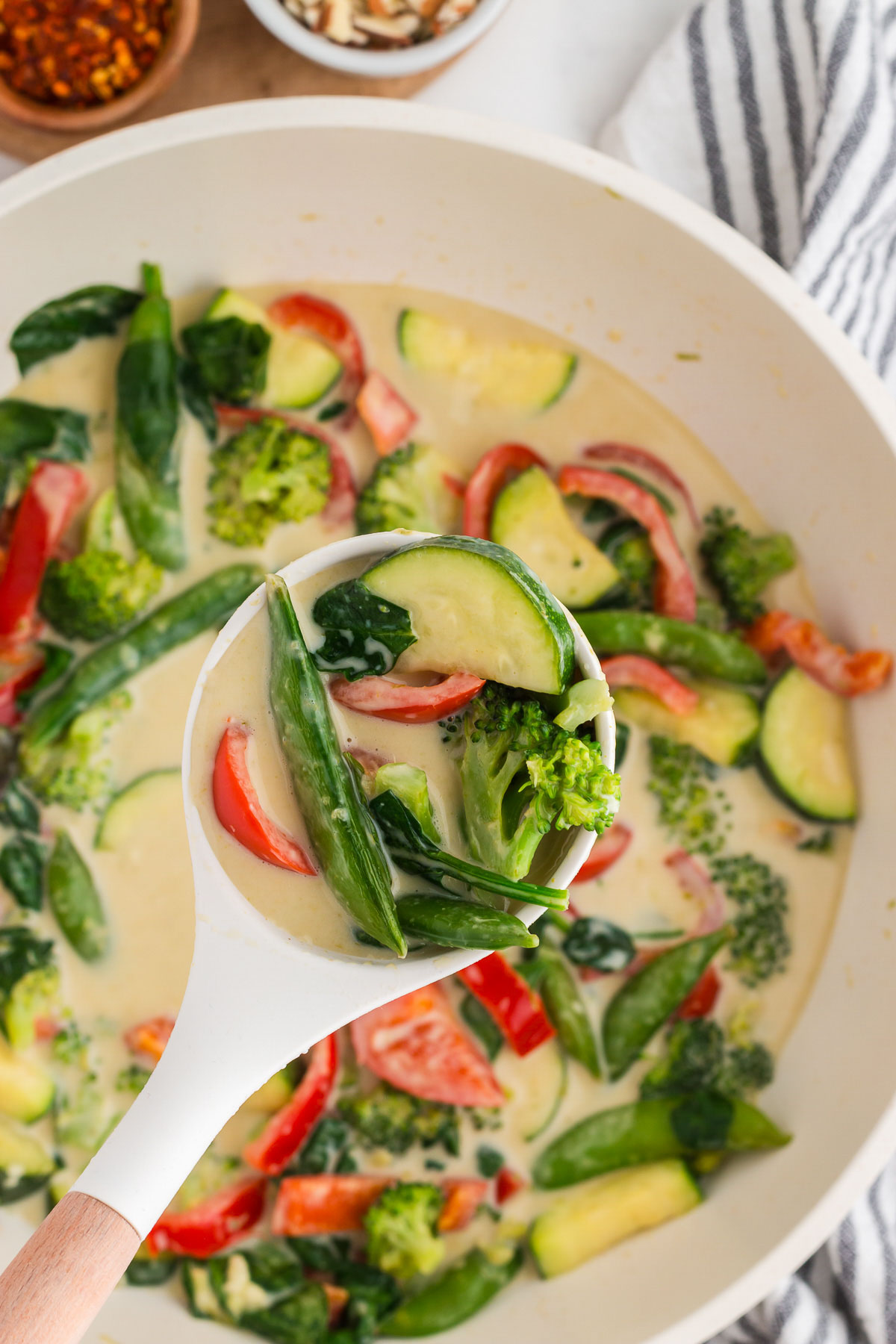 Thai green curry with coconut milk being scooped out of a saucepan and ready to serve.