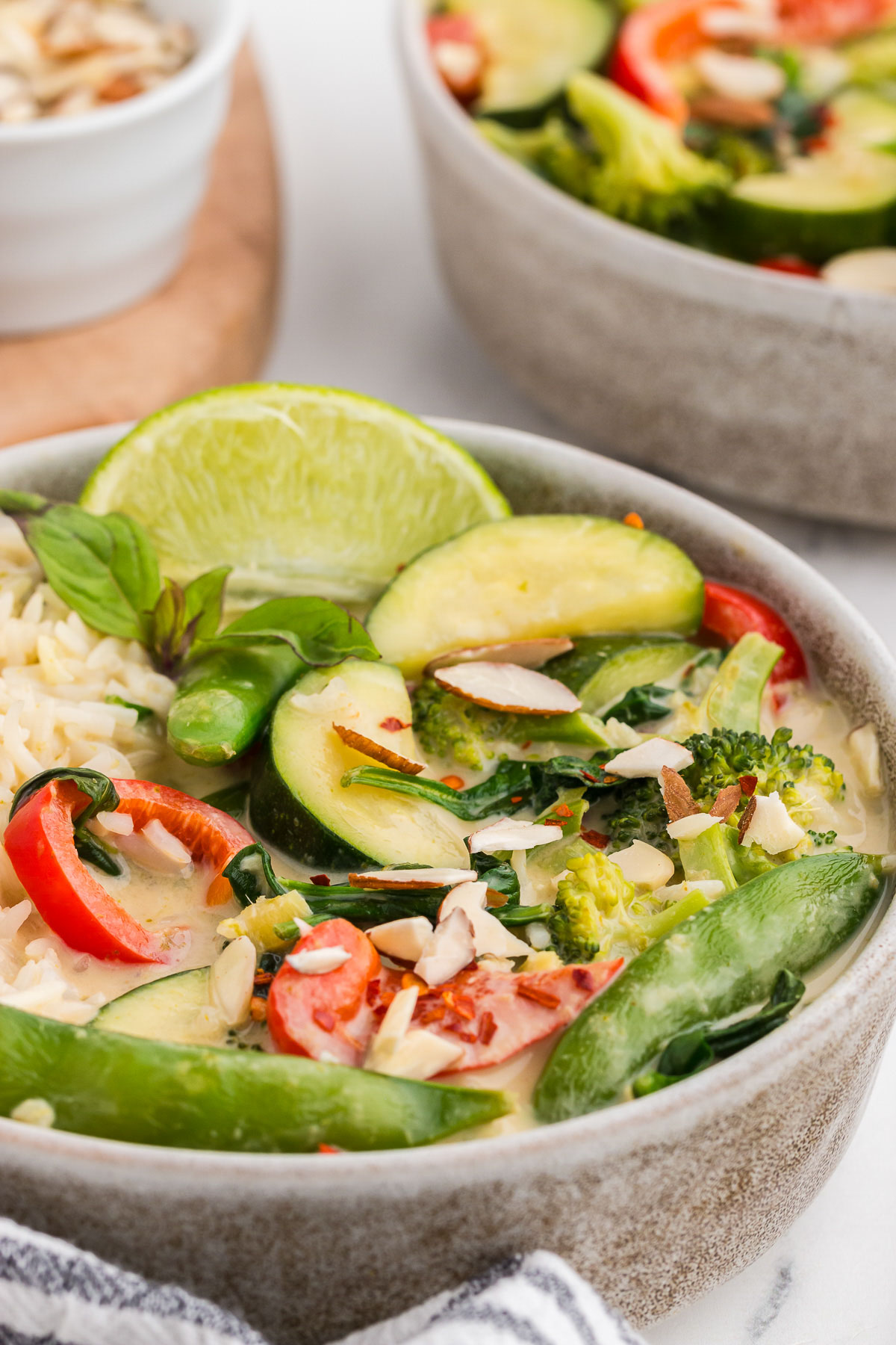 A rustic bowl full of Thai Green Curry Vegetables and brown rice.