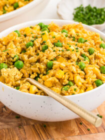A white bowl full of tofu fried rice on a wooden board.