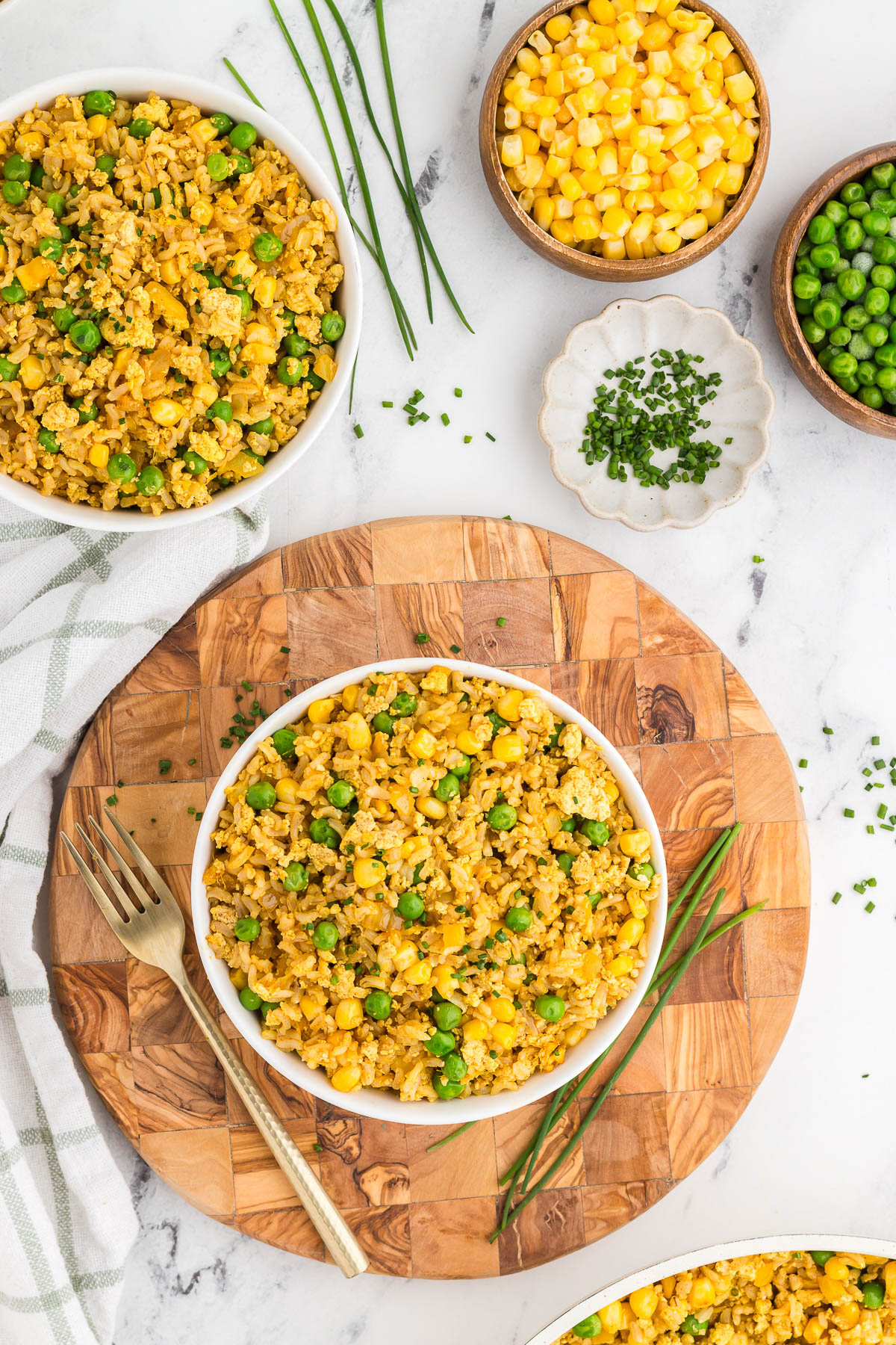Top view of tofu fried rice on a round wooden board with a gold fork