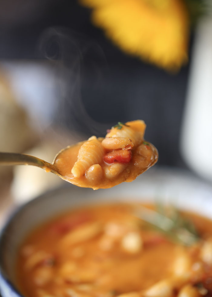A spoonful of vegan pasta e fagioli steams as it's being served. 