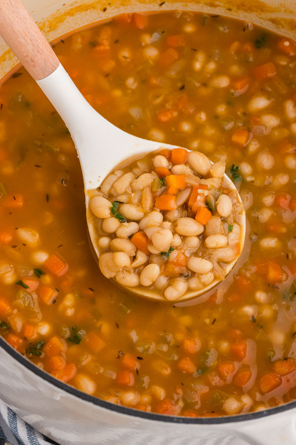 Vegetarian Navy Bean Soup in a pot with a ladle scooping out a serving.