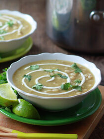 Two bowls of vegetarian chili verde on a wooden cutting board.