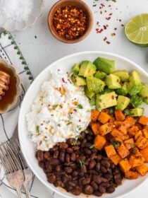 Viral Cottage Cheese Bowl in a white bowl with ingredients in the background with pepper flakes in a bowl next to it