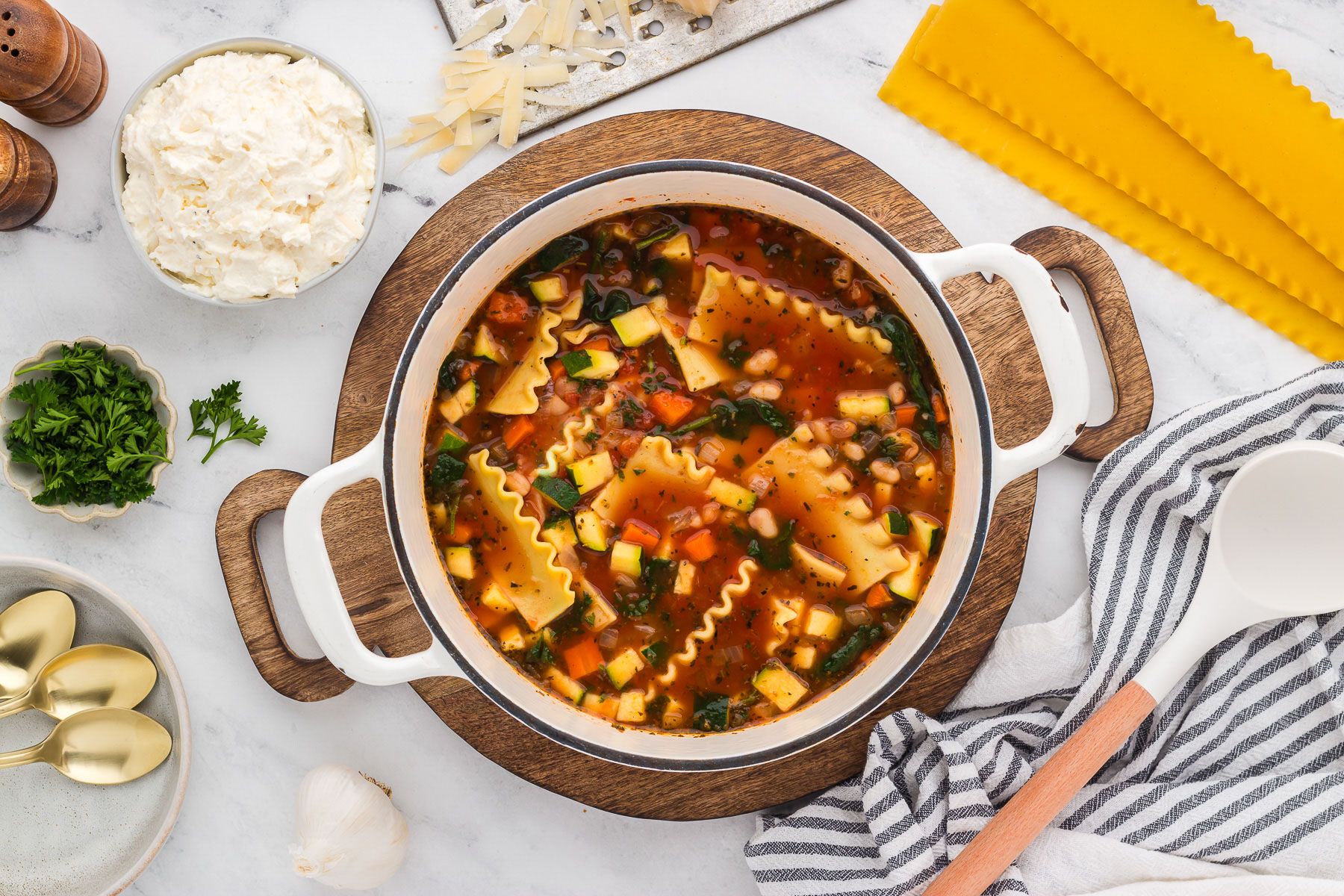 A white pot full of veggie lasagna soup.