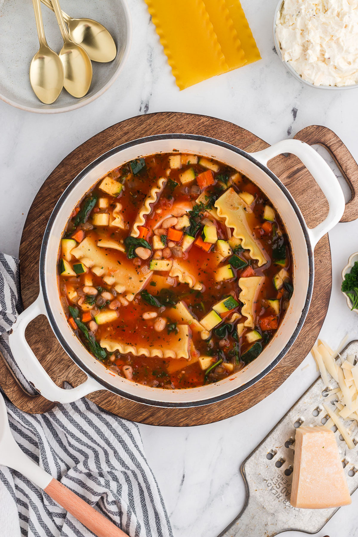A white pot full of veggie lasagna soup.