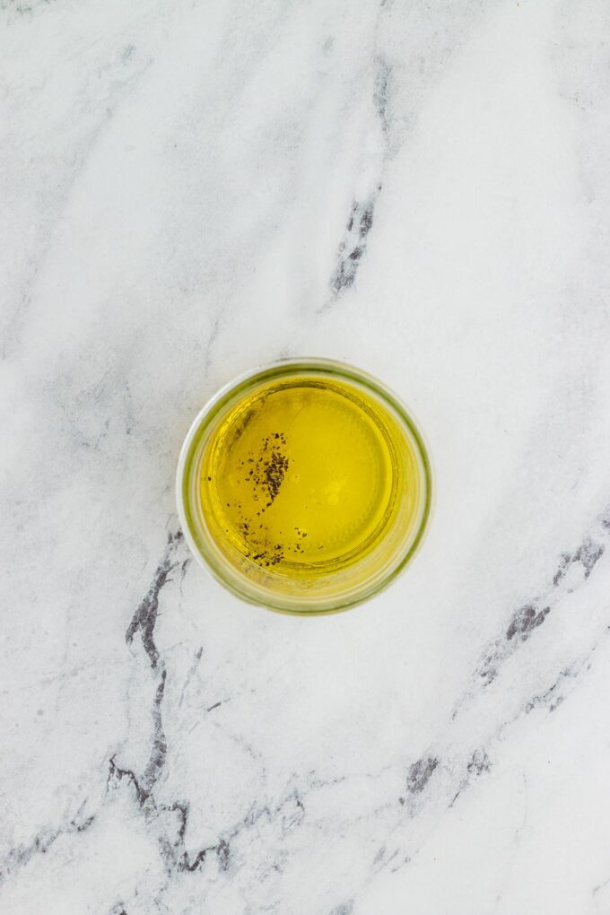 Ingredients being added to a mason jar for homemade vinaigrette