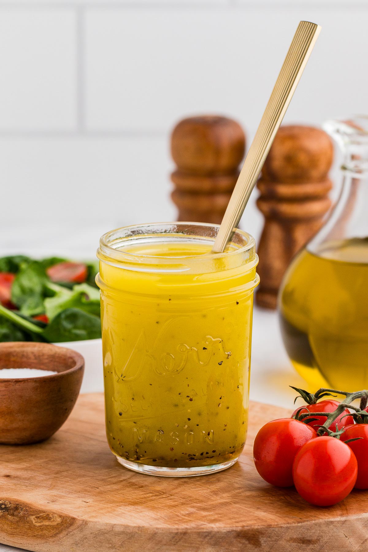Homemade vinaigrette in a mason jar with a gold spoon in the jar