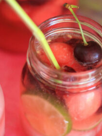 A jar of watermelon sangria against a bright pink background.