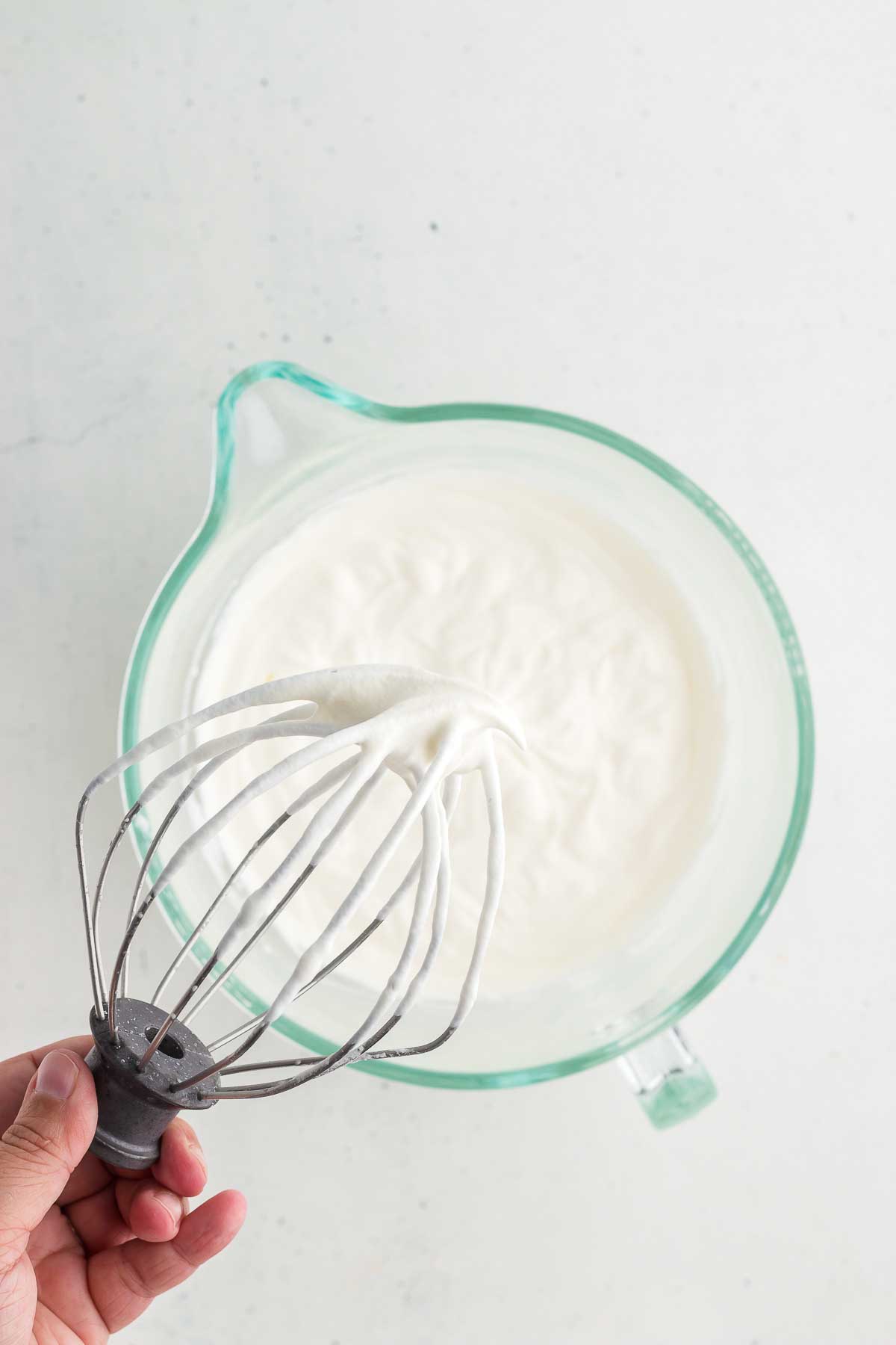A whisk showing that heavy whipped cream has been whipped well and thickened