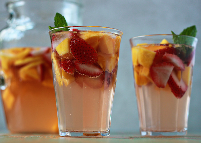 Two glasses of summer sangria with a pitcher in the background. 
